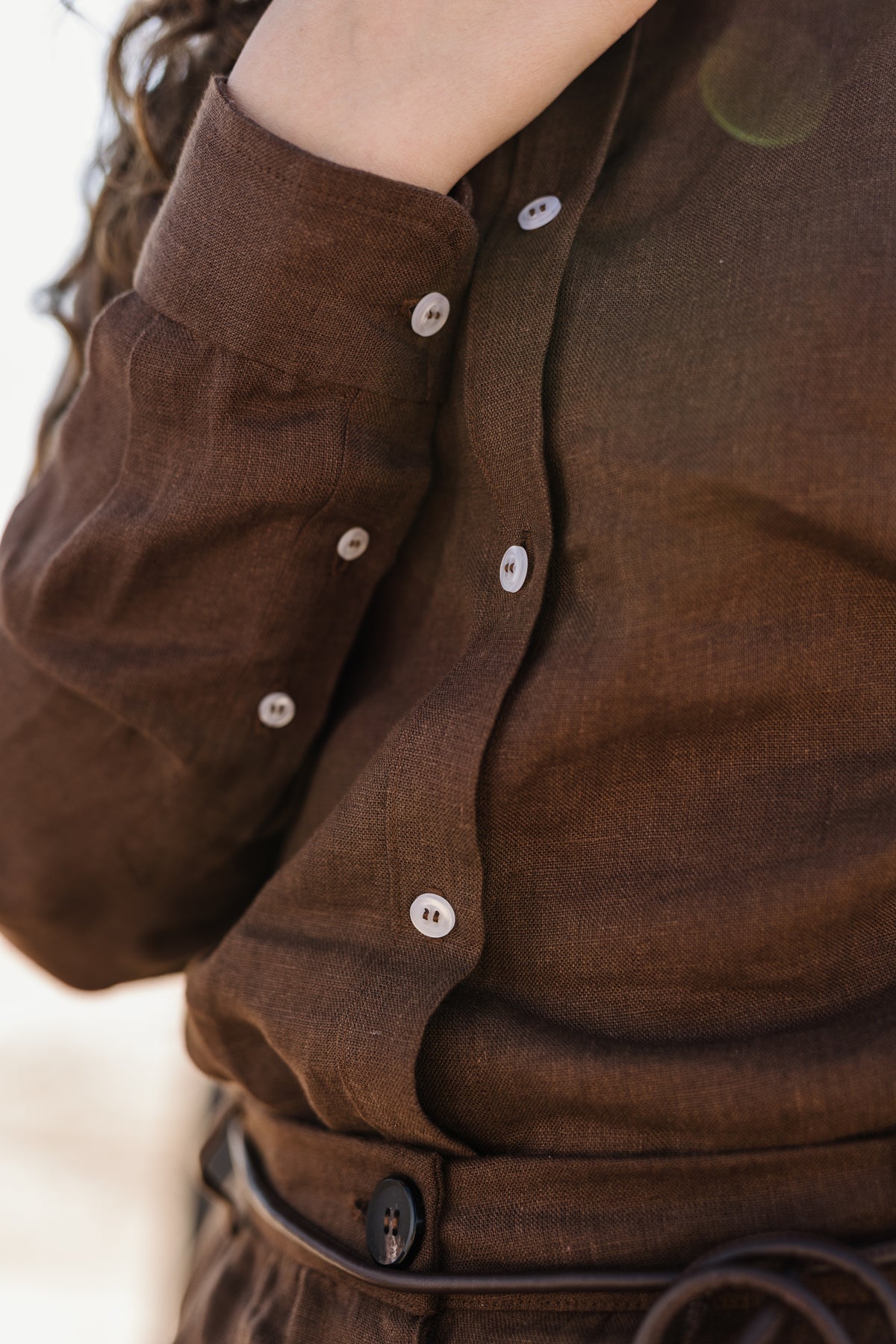 Close-up of a person wearing a matching Lowveld Umber 100% European brown linen button-up shirt and  Lowveld Umber 100% European brown linen pants.