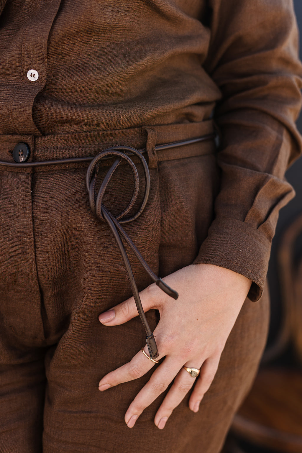 A close-up of a person wearing a matching Lowveld Umber 100% European brown linen button-up shirt and  Lowveld Umber 100% European brown linen pants
