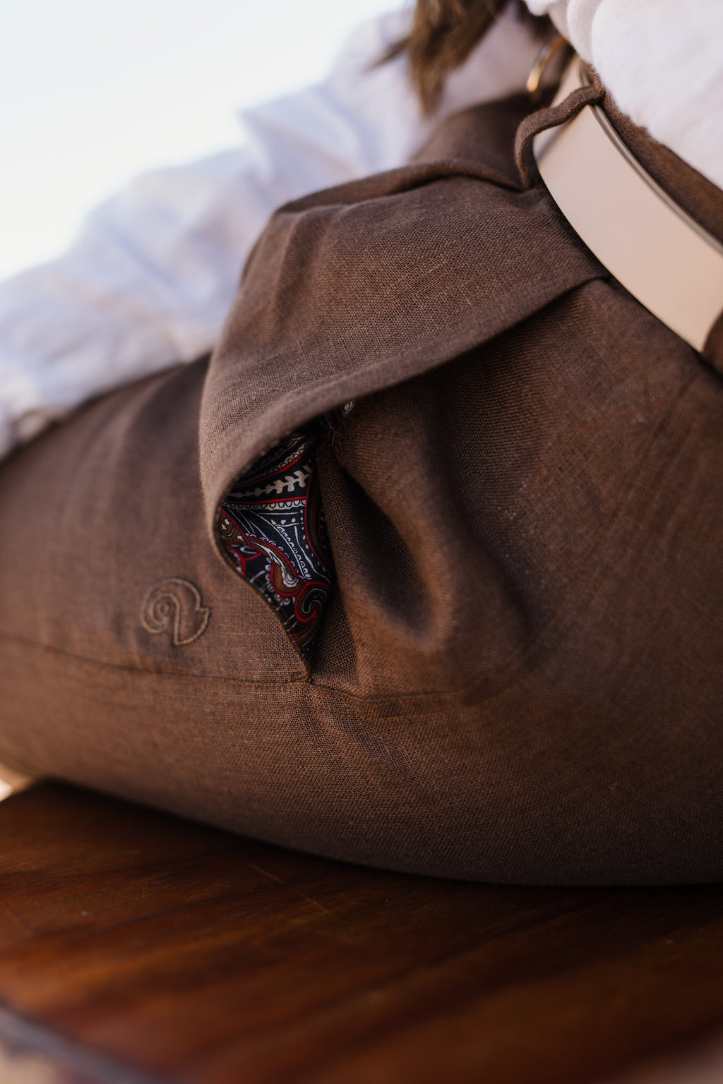 A close-up shot of a Lowveld Umber 100% European brown linen shorts with a pocket, showing a patterned fabric lining of the pocket